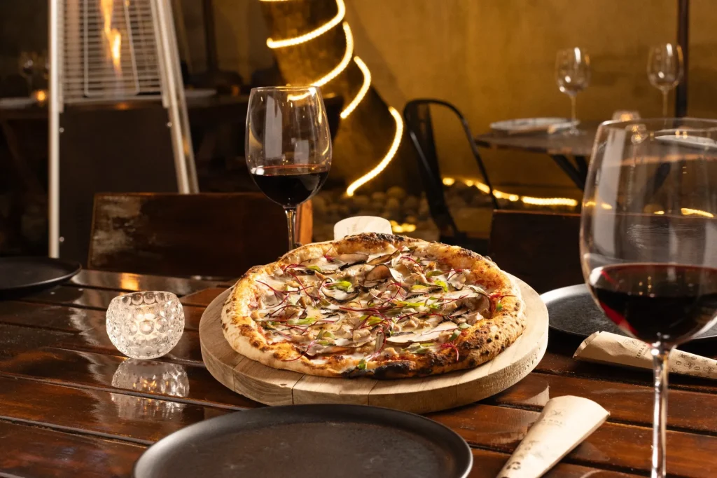 Pizza gourmet y vino en terraza iluminada en Zona 14 Guatemala